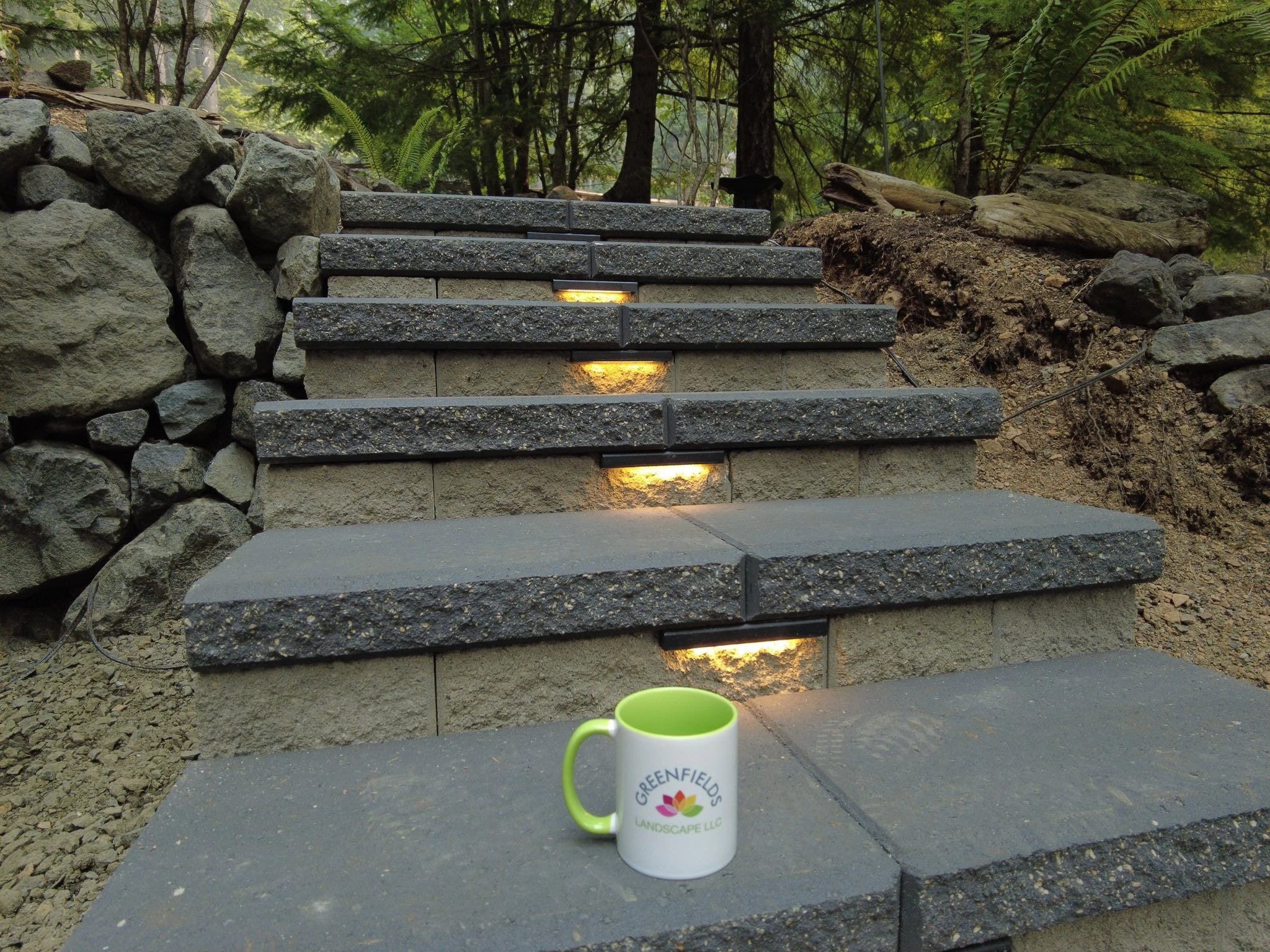 Illuminated stone steps with Greenfields Landscape branding — professional outdoor lighting installation